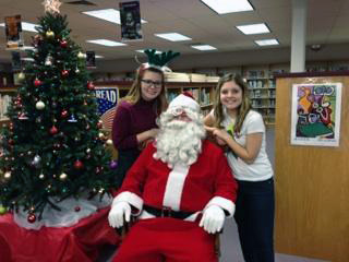 Volunteers in Paupack club members from Wallenpaupack Area High School take a break from wrapping Christmas gifts to visit Santa Claus. From left: Breonna Arnold and Taylor Regenski.